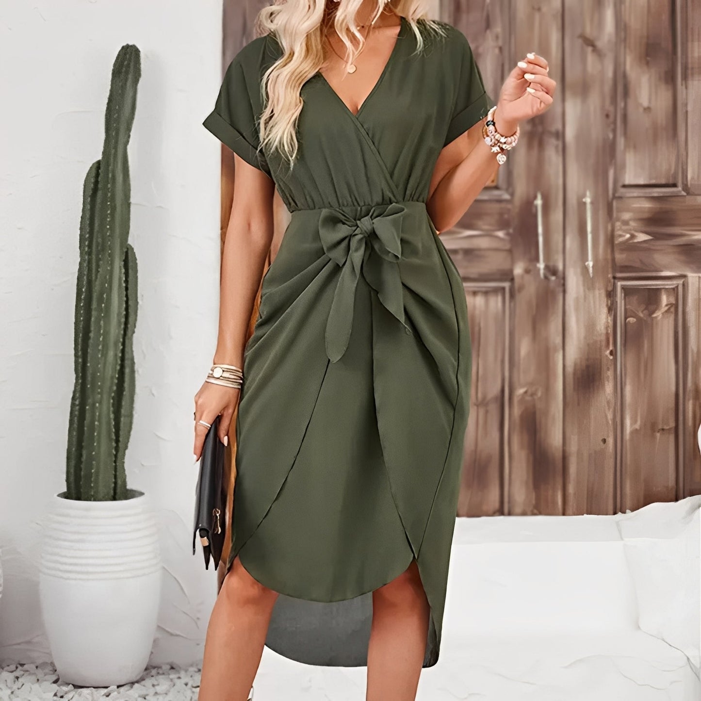 Woman wearing a green dress with a wooden panel and cactus in the background