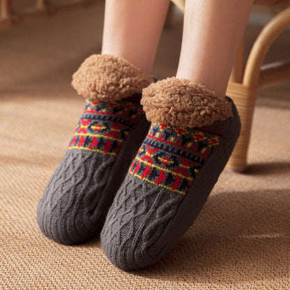 Gray cable knit socks with patterned cuffs worn indoors on a carpeted floor.
