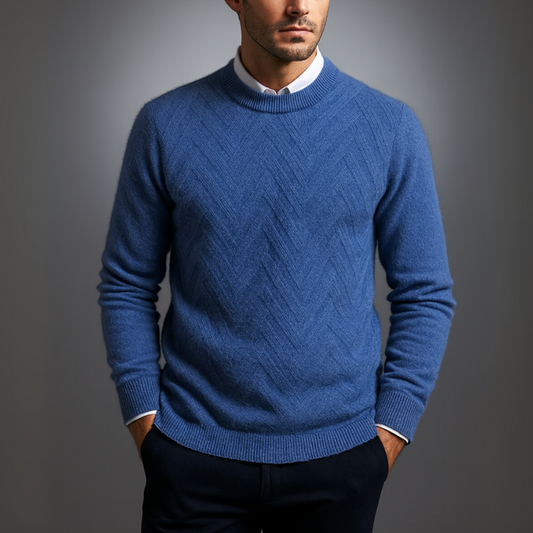 Man wearing a blue patterned sweater against a gray background