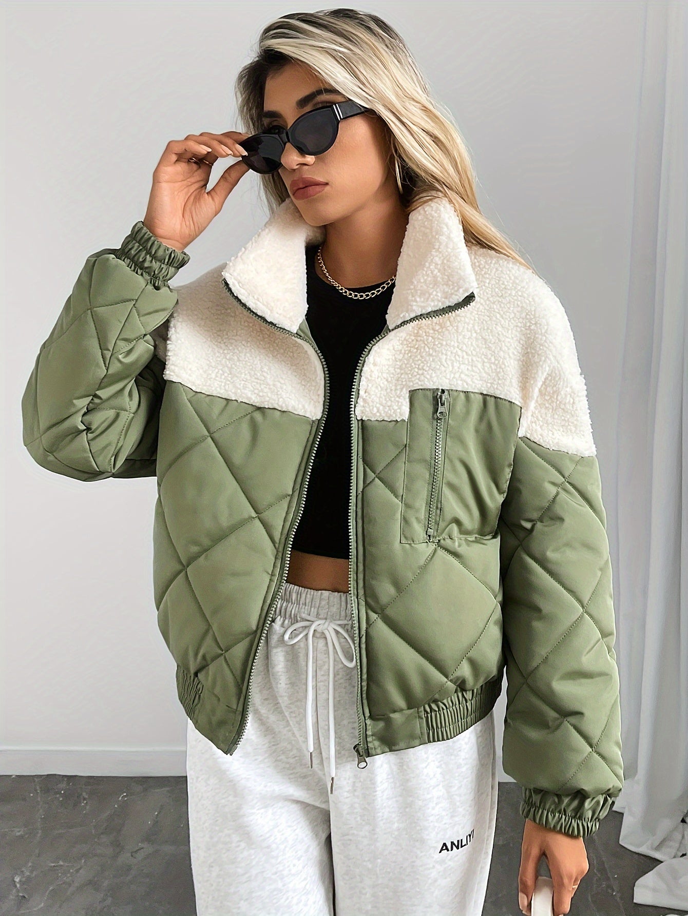 Person wearing a green and white quilted jacket with a plain background