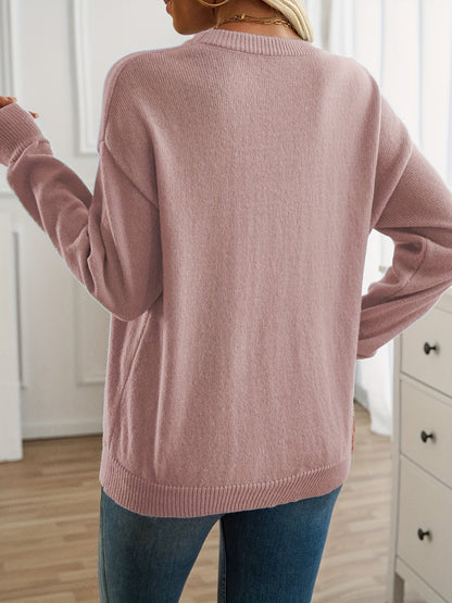Person wearing a pink sweater in a room with white walls and furniture.