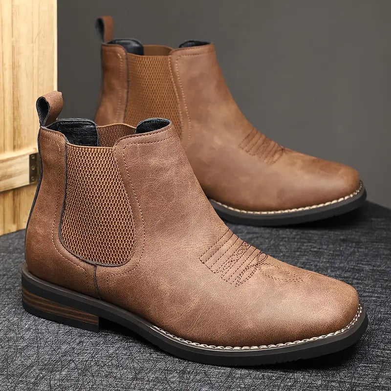 Brown leather Chelsea boots on a textured surface with a neutral background