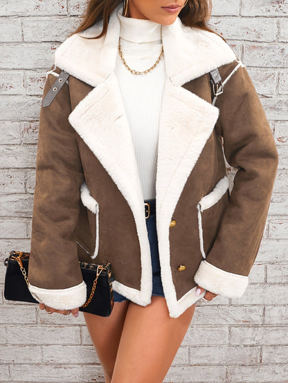 Brown shearling jacket with white trim worn by a person against a light brick wall.