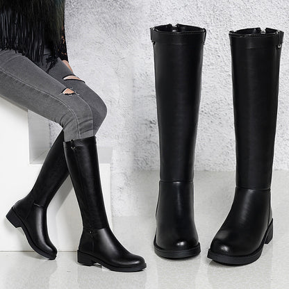 Black knee-high boots displayed on a light gray surface with a neutral background.