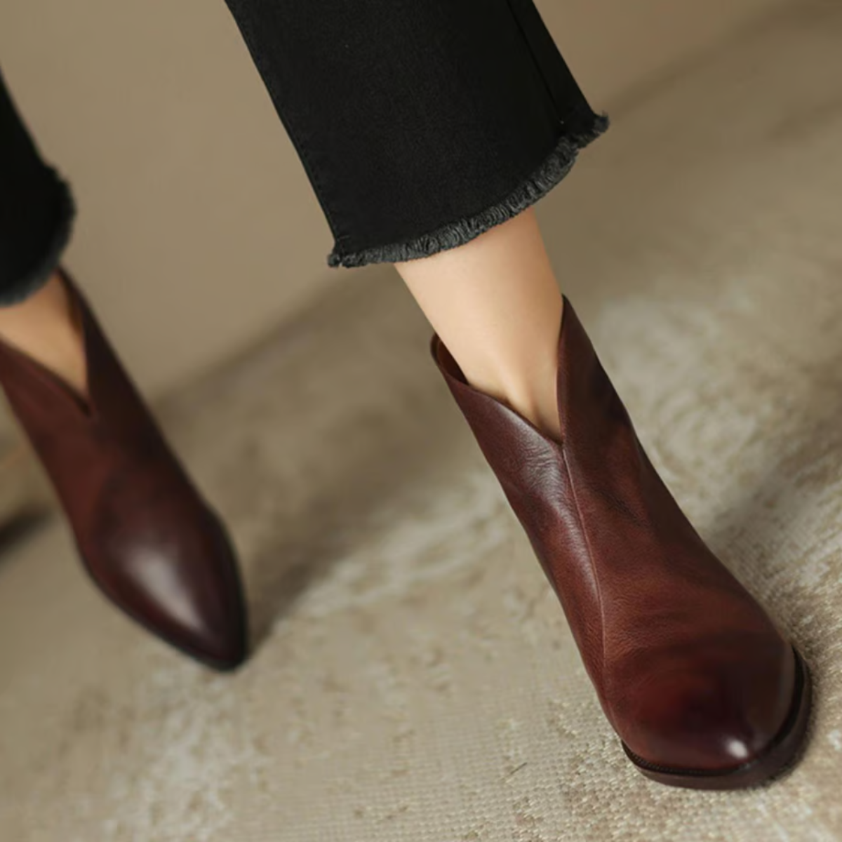 Brown leather ankle boots worn with black jeans on a neutral background