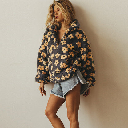 Woman wearing a floral hoodie and denim shorts against a plain background