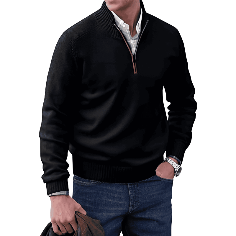 Man wearing a black quarter-zip sweater and blue jeans on a white background