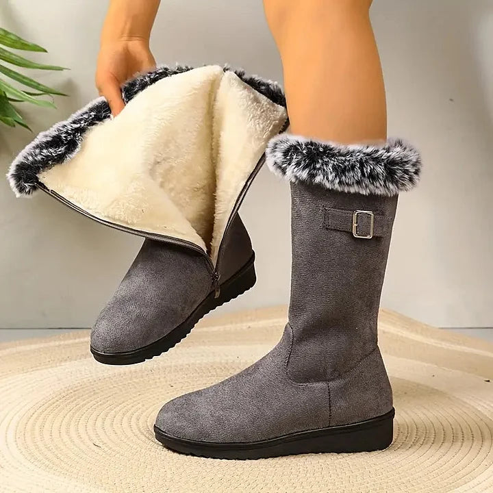 Gray suede boots with fur trim on a neutral background