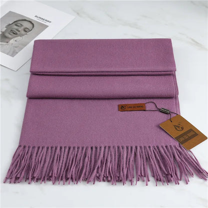 Purple scarf with fringes and a tag on a white surface
