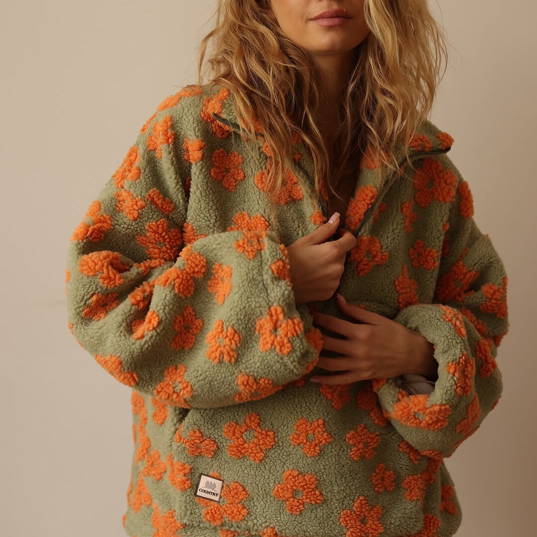 Person wearing a green fleece jacket with orange floral patterns on a beige background
