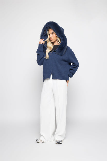 Person wearing a blue hoodie with a fur-lined hood on a white background