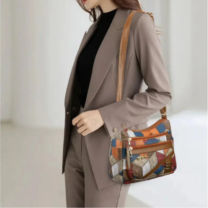 Person wearing a brown coat holding a colorful patterned handbag against a white background