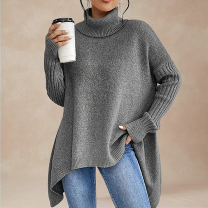 Person wearing a gray turtleneck sweater holding a white cup against a beige background