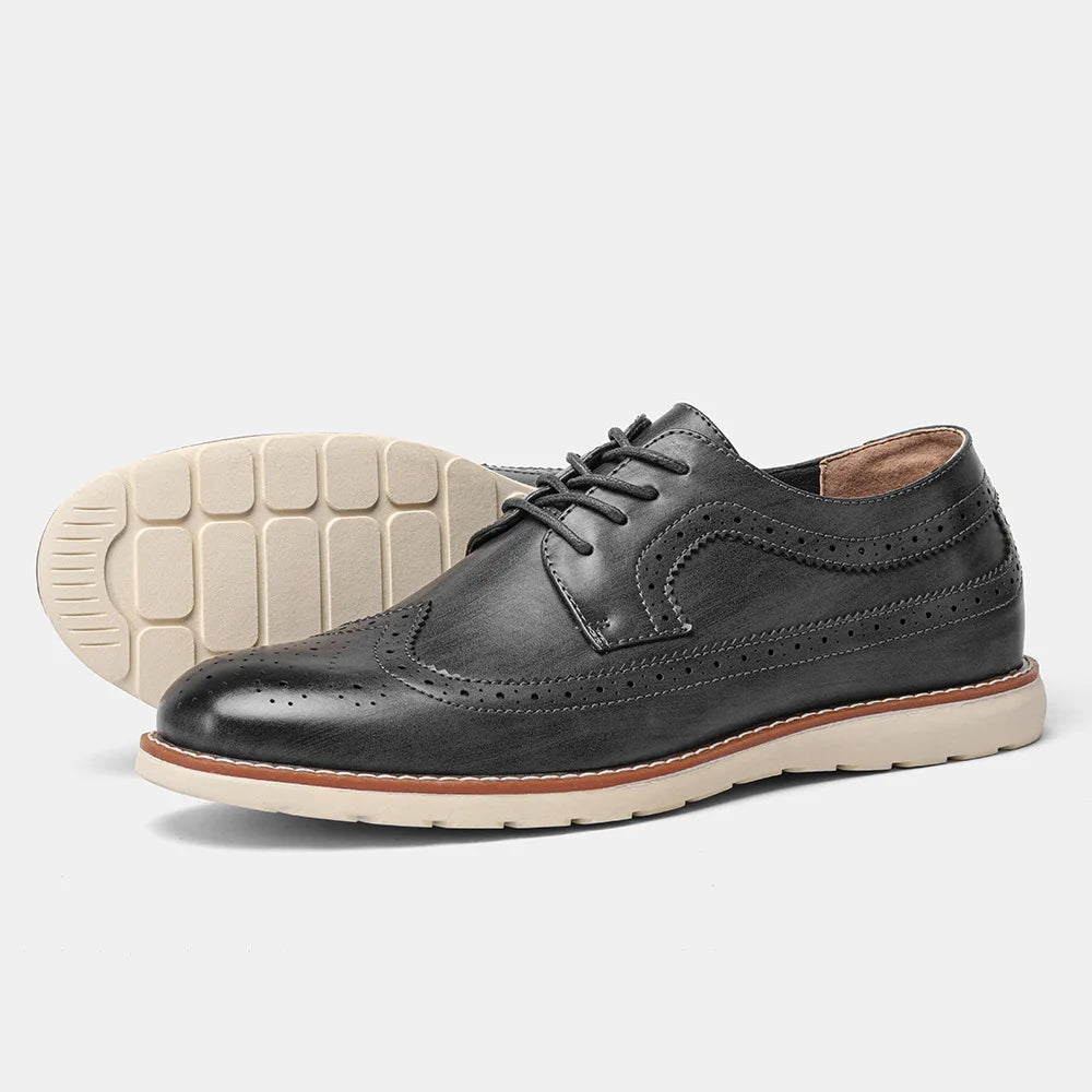 Black leather brogue shoes with white soles on a light gray background