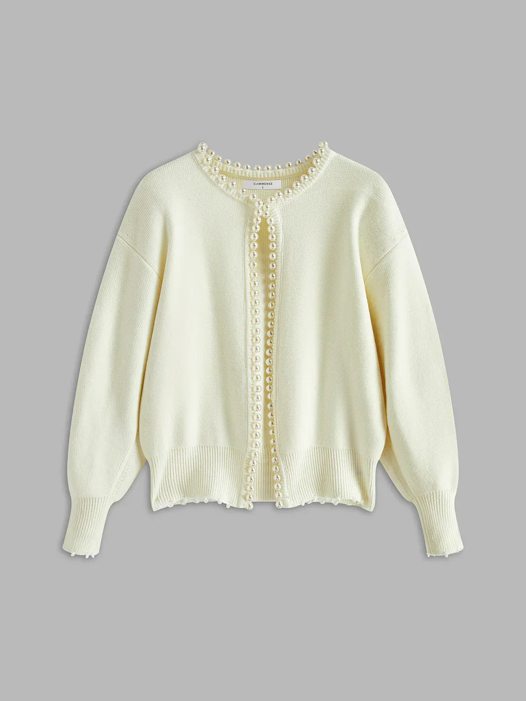 Light yellow sweater with button details on a gray background