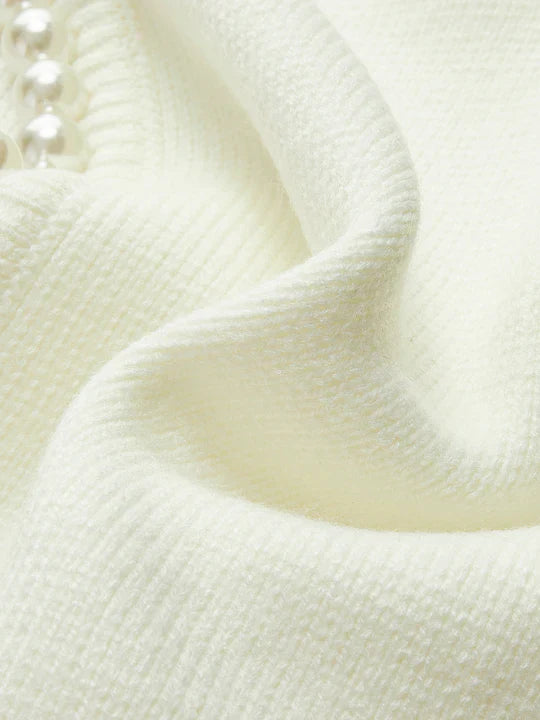 Close-up of textured white fabric with a pearl-like bead.