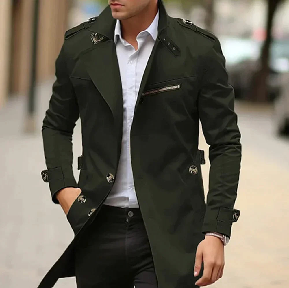 Man wearing a green trench coat over a white shirt on a blurred street background