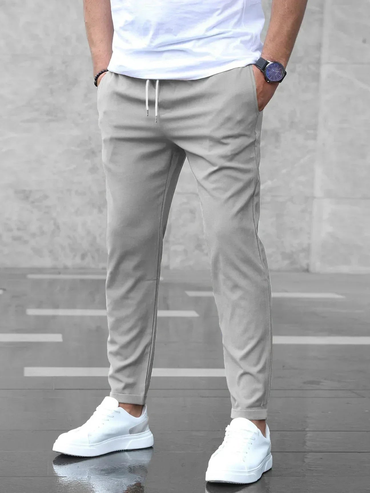 Person wearing light gray jogger pants with a plain background
