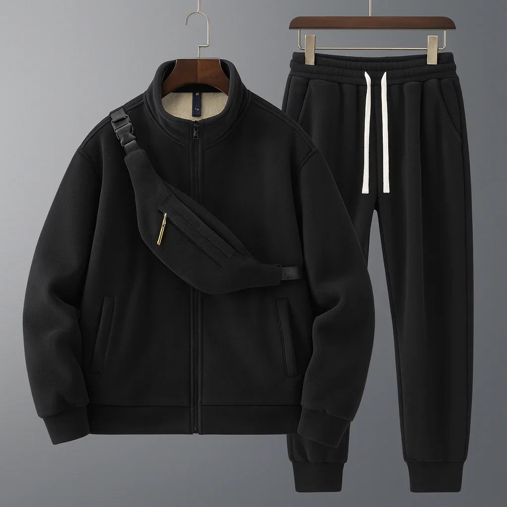 Black tracksuit with jacket and pants on hangers against a gray background