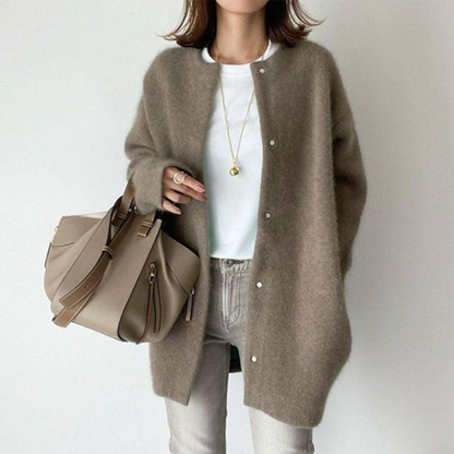 Person wearing a brown cardigan with a beige handbag on a plain background