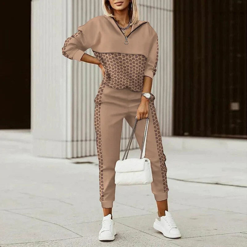 Woman wearing a brown and patterned tracksuit with white sneakers, holding a white handbag.