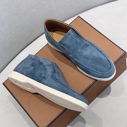 Blue suede loafers on a brown box with a gray background