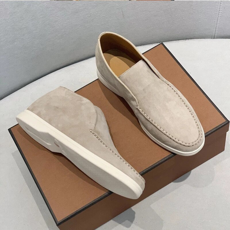 Pair of beige loafers on a brown shoe box with a gray background