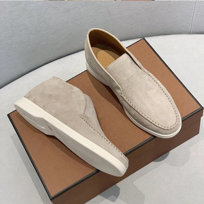 Pair of beige loafers on a brown shoe box with a gray background