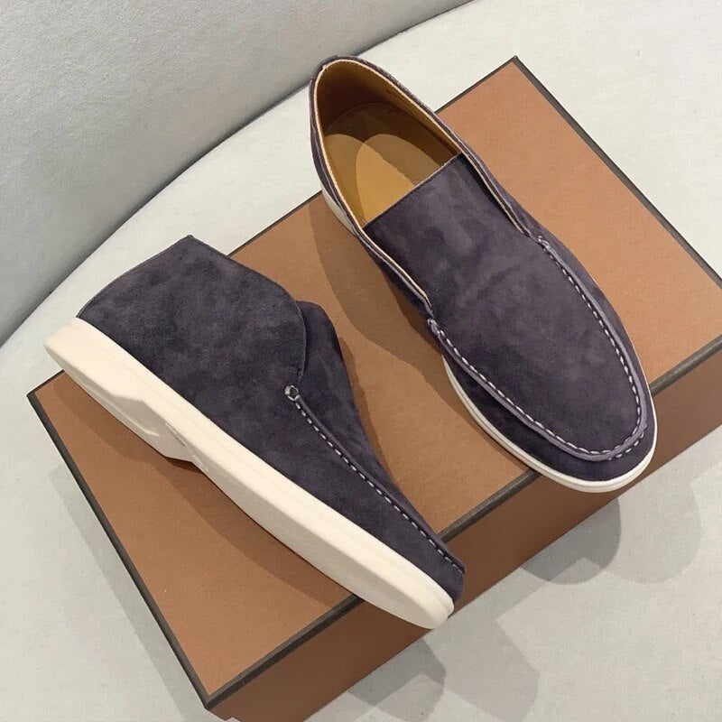 Pair of dark blue suede loafers on a brown box with a gray background