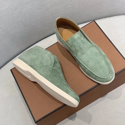 Pair of green loafers on a brown box with a gray background