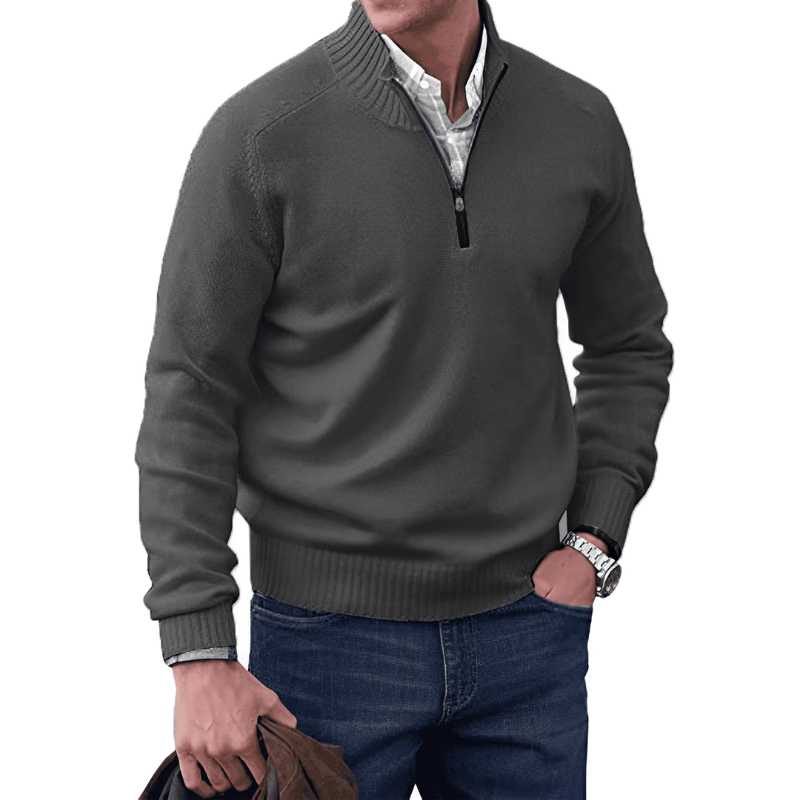 Man wearing a gray sweater over a white shirt with blue jeans on a white background