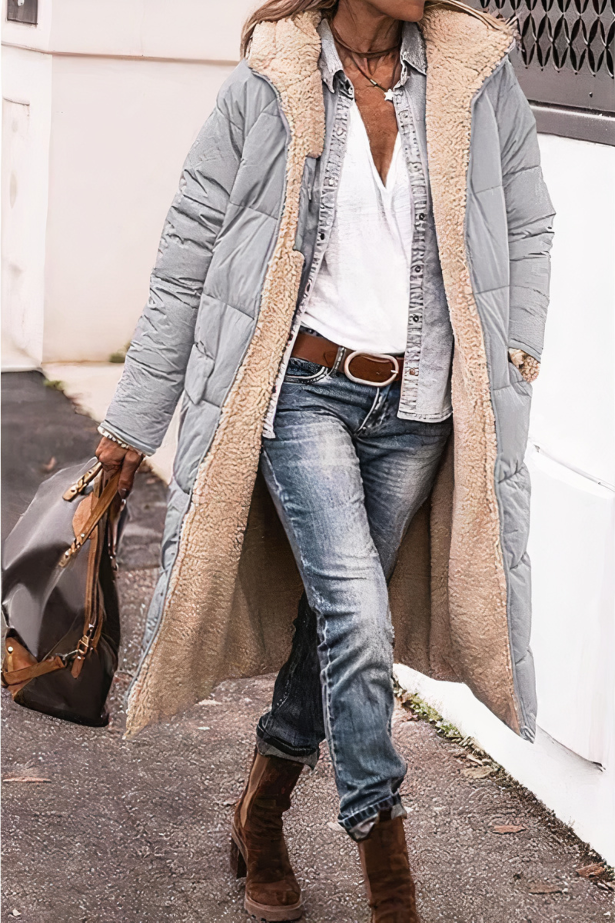 Person wearing a long gray puffer coat with a fur-lined hood, blue jeans, and brown boots.