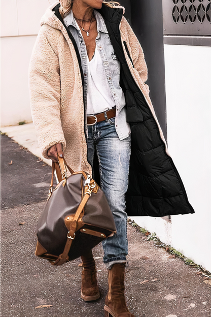 Person wearing a beige coat with a black lining, holding a handbag on a sidewalk.