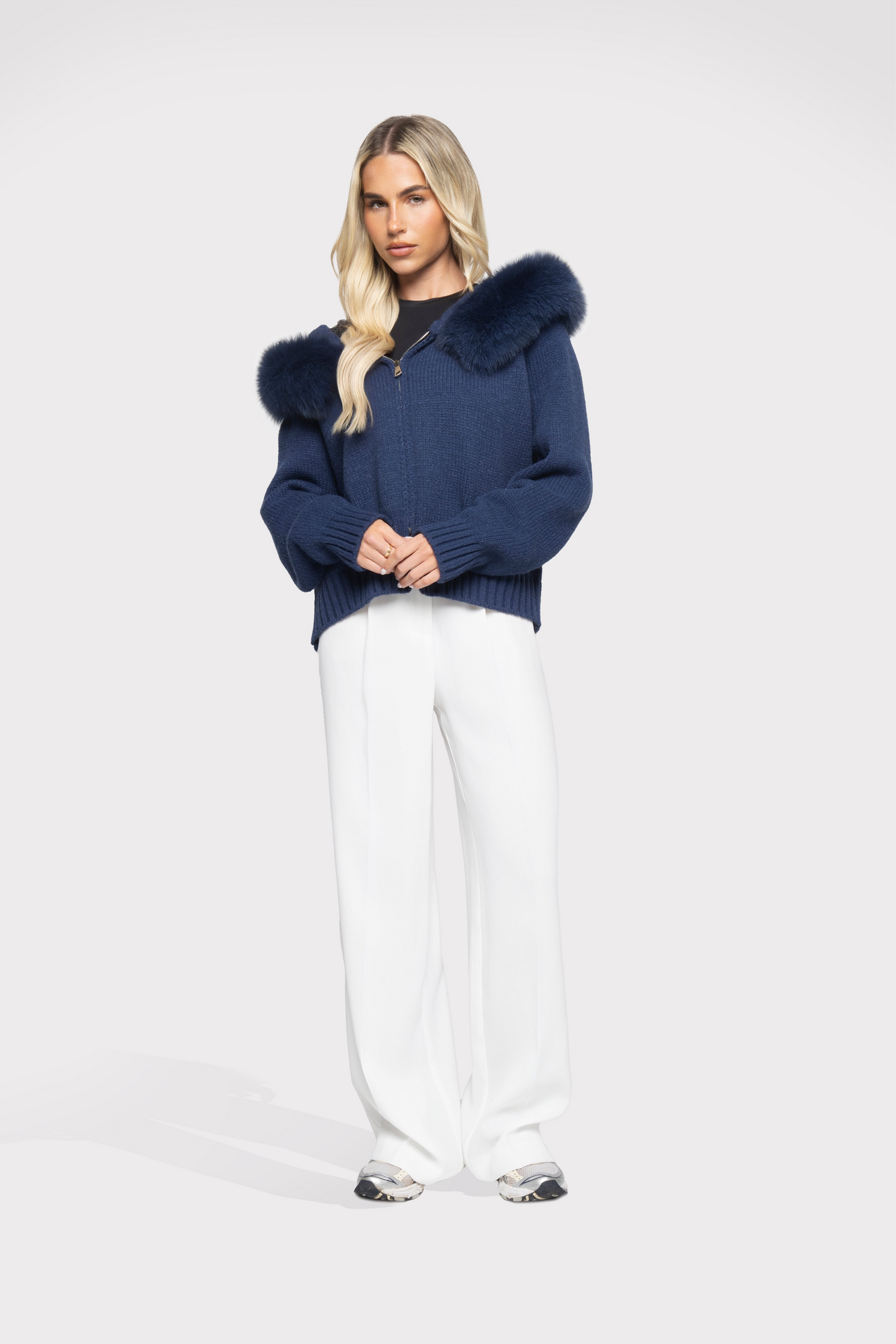 Woman wearing a navy blue sweater with fur trim on a white background