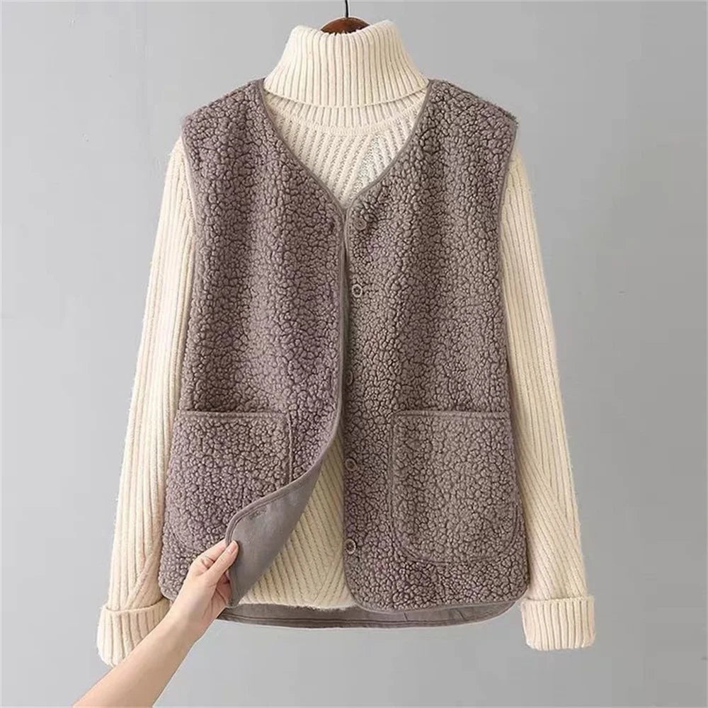 Brown fleece vest over a cream sweater on a gray background