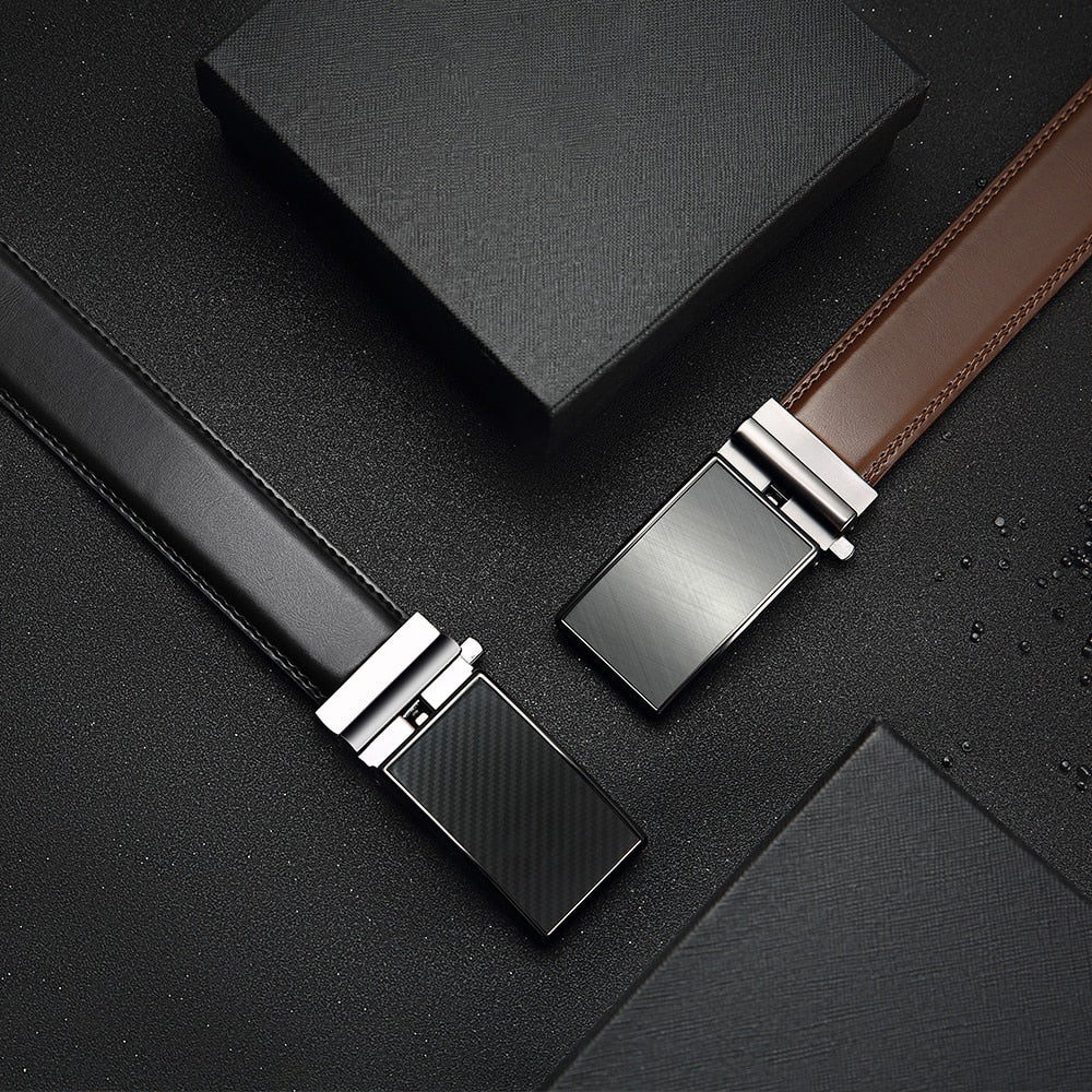 Two belts with black and silver buckles on a dark surface
