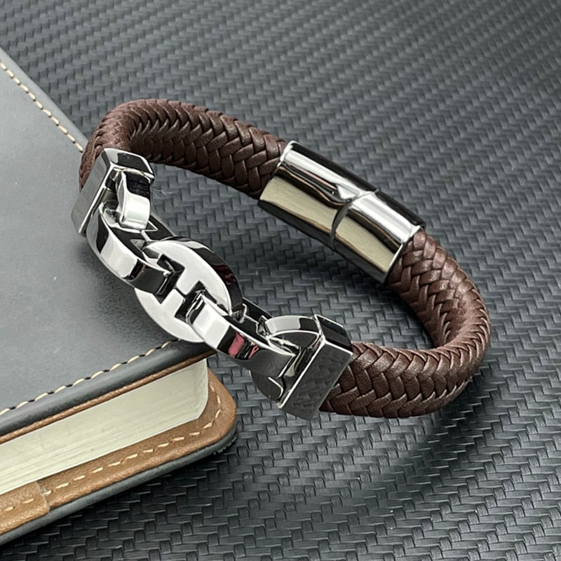 Brown braided leather bracelet with silver clasp on a textured surface