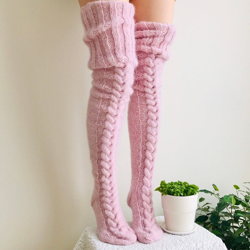 Pink knitted knee-high socks worn by a person with a blurred background
