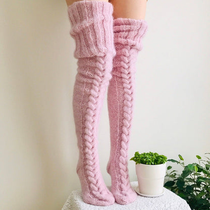 Pink knitted knee-high socks worn by a person with a blurred background