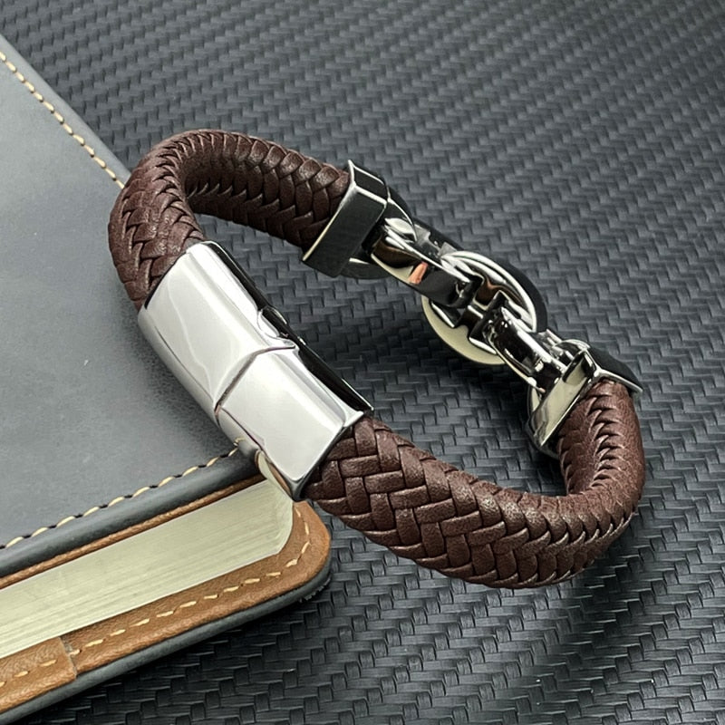 Brown braided leather bracelet with silver clasp on a textured surface