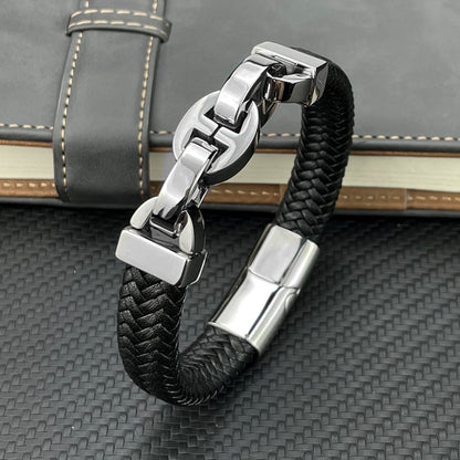 Black braided leather bracelet with silver clasp on a textured surface