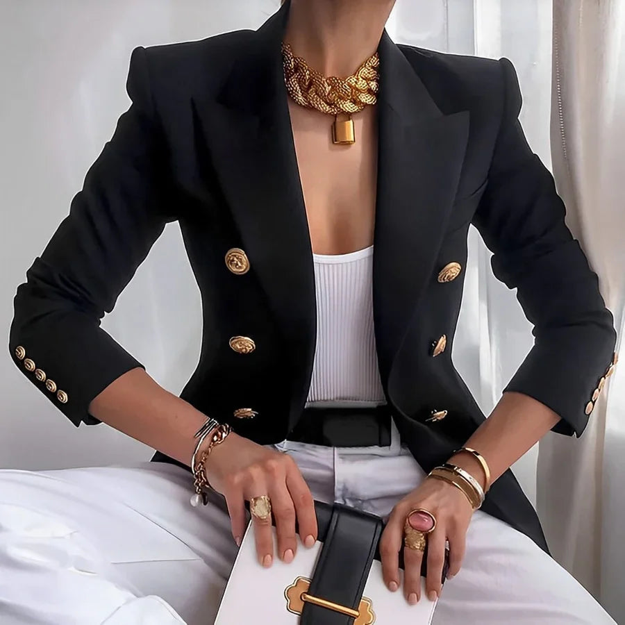 Person wearing a black blazer with gold buttons and holding a black handbag with gold accents.