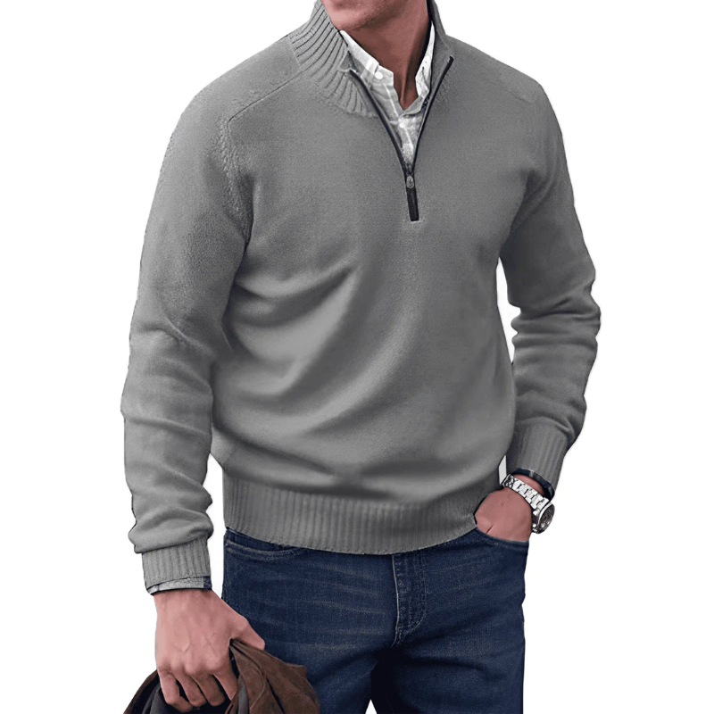 Man wearing a gray sweater with a zipper, white shirt, and blue jeans on a white background