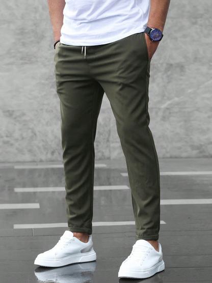 Person wearing olive green pants and white sneakers against a gray background