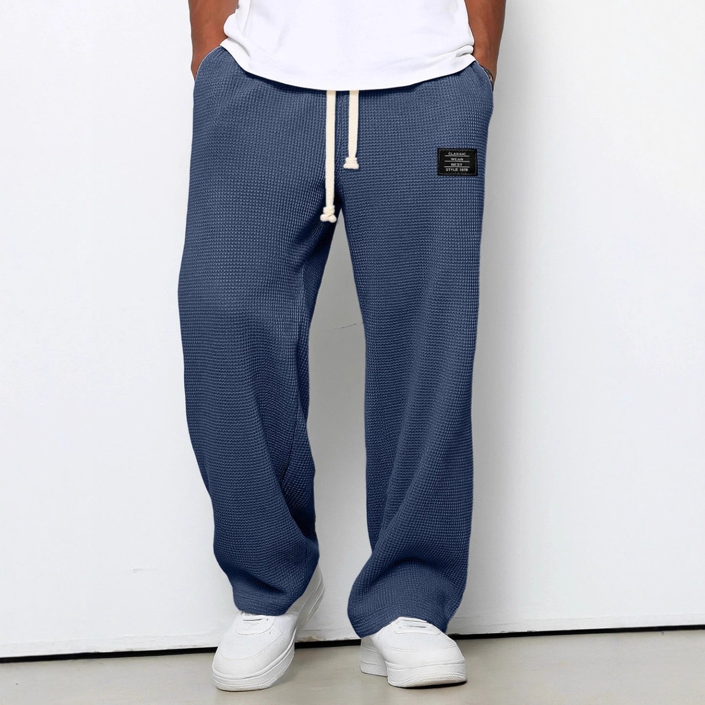 Person wearing blue textured sweatpants with a white label on a white background