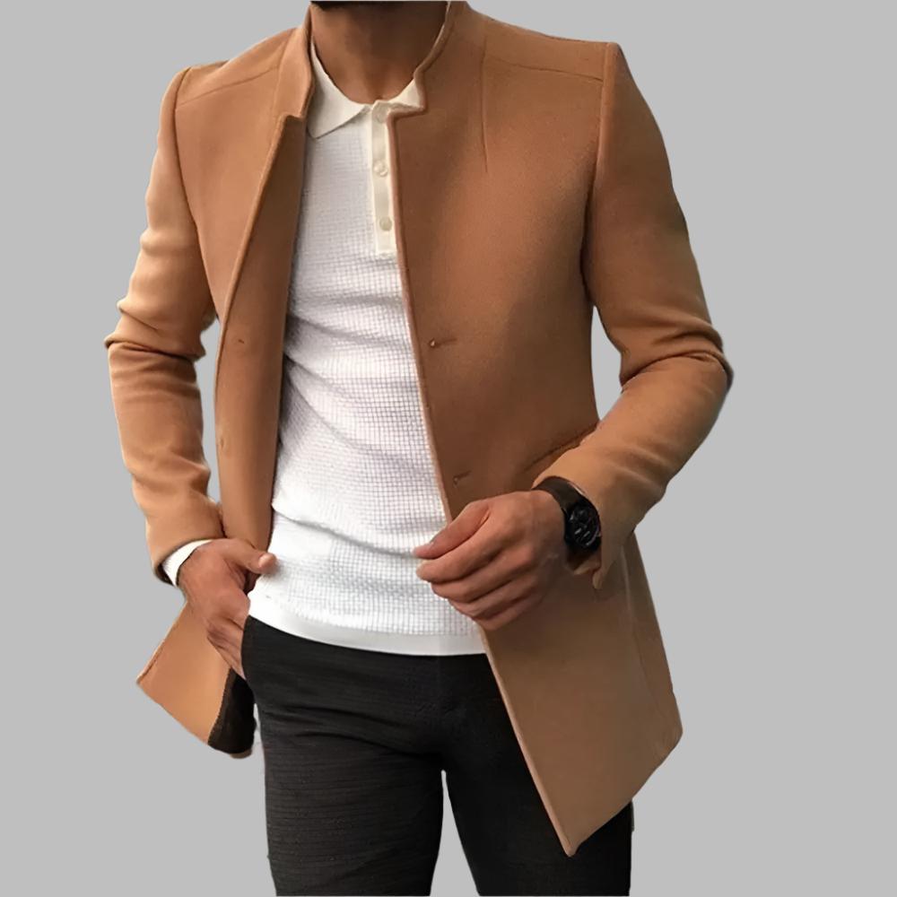 Person wearing a tan coat over a white shirt and black pants on a gray background