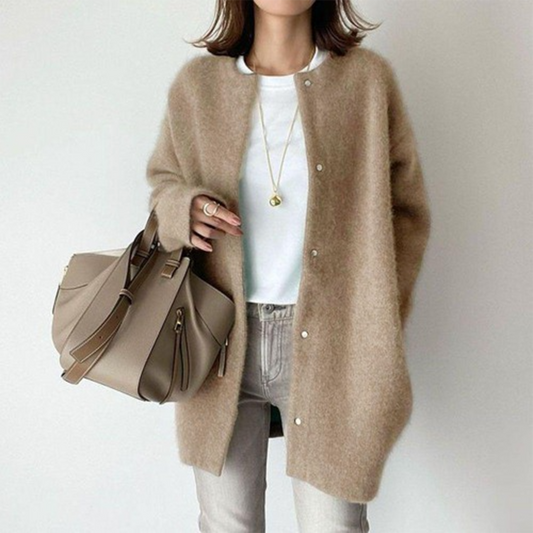 Person wearing a beige cardigan holding a matching handbag on a plain background