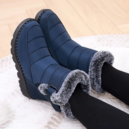 Blue winter boots with fur trim worn by a person on a light background