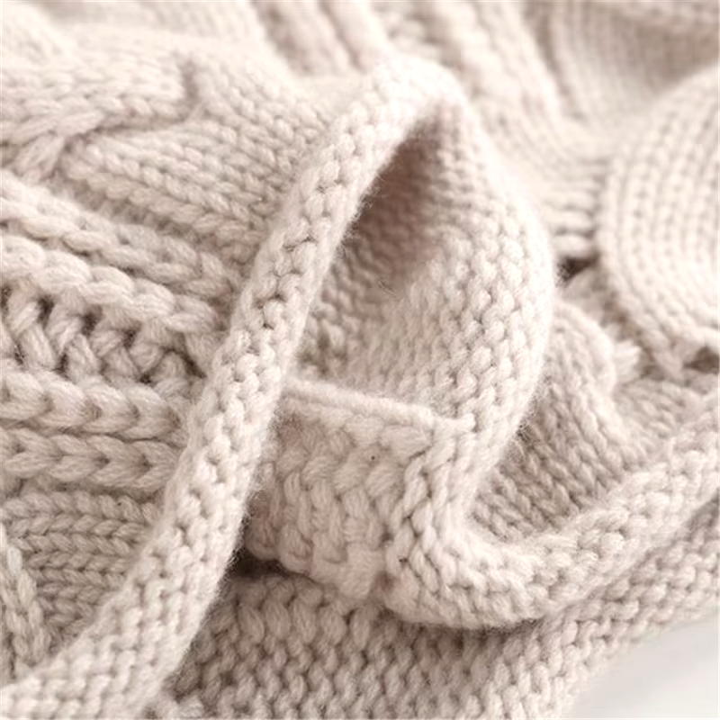 Close-up of a beige knitted blanket with a textured pattern.