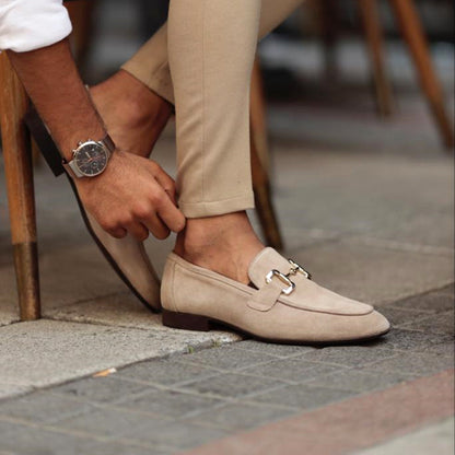 Person wearing a beige loafer shoe on a sidewalk